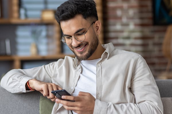 A man sitting on a couch on his phone.
