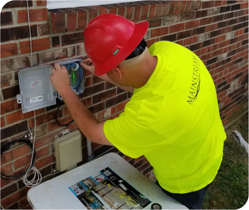 Image of a Mainstream Fiber installer activating a customer's internet by splicing the fiber at the side of their house.