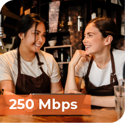 An image that says, "250 Mbps" featuring two young baristas working together on a tablet.