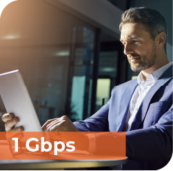 An image that says, "1 Gbps" and features a successful middle aged business man doing work on a computer at his desk.