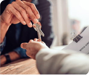 An image showing two people handing keys to a building to one another.