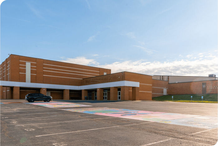 West Washington School building with a black vehicle in the parking lot