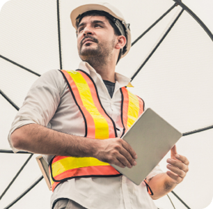 Picture of a male construction worker holding tablet and looking off into distance confidently