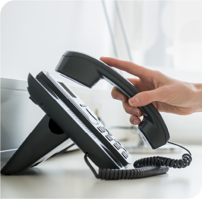 Picture of woman's hand picking up a business phone from its receiver.