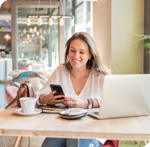 Smiling businessman on phone with computer at coffee shop