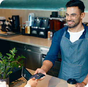 smiling businessman completing a transaction with customer using a credit card