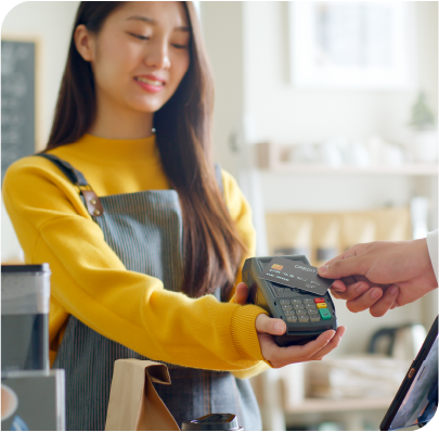 Picture of a young woman cashier accepting payment on a wireless card reader.