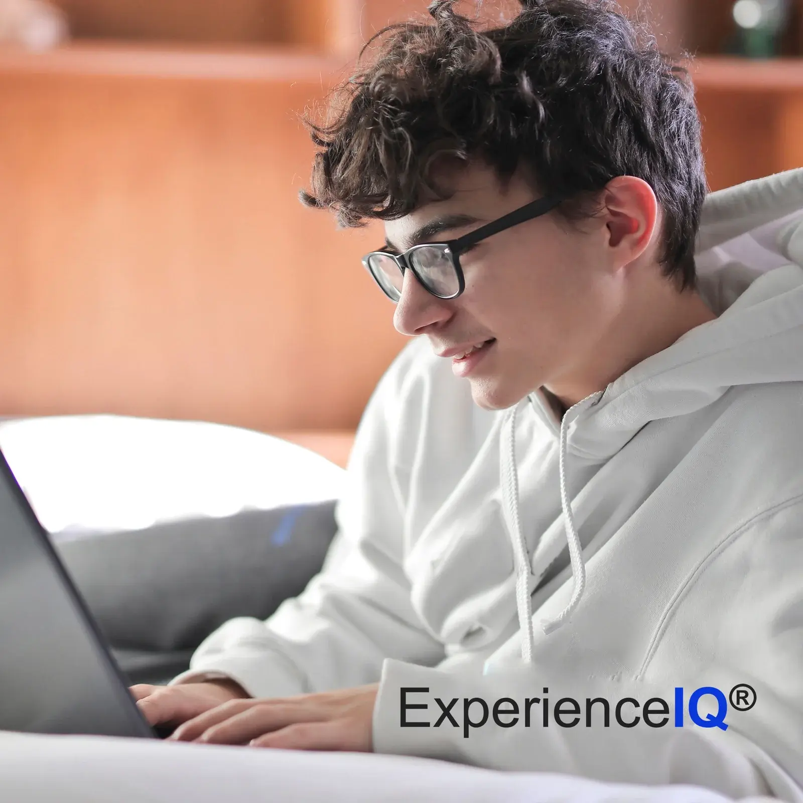 Image that says, "ExperienceIQ" and has a teenage boy with glasses working on laptop