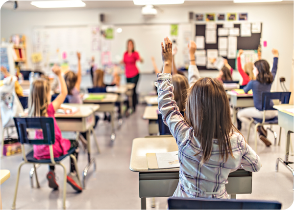 children in classroom raising hand